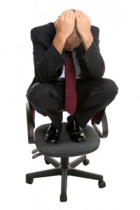 Businessman crouched on a chair.
